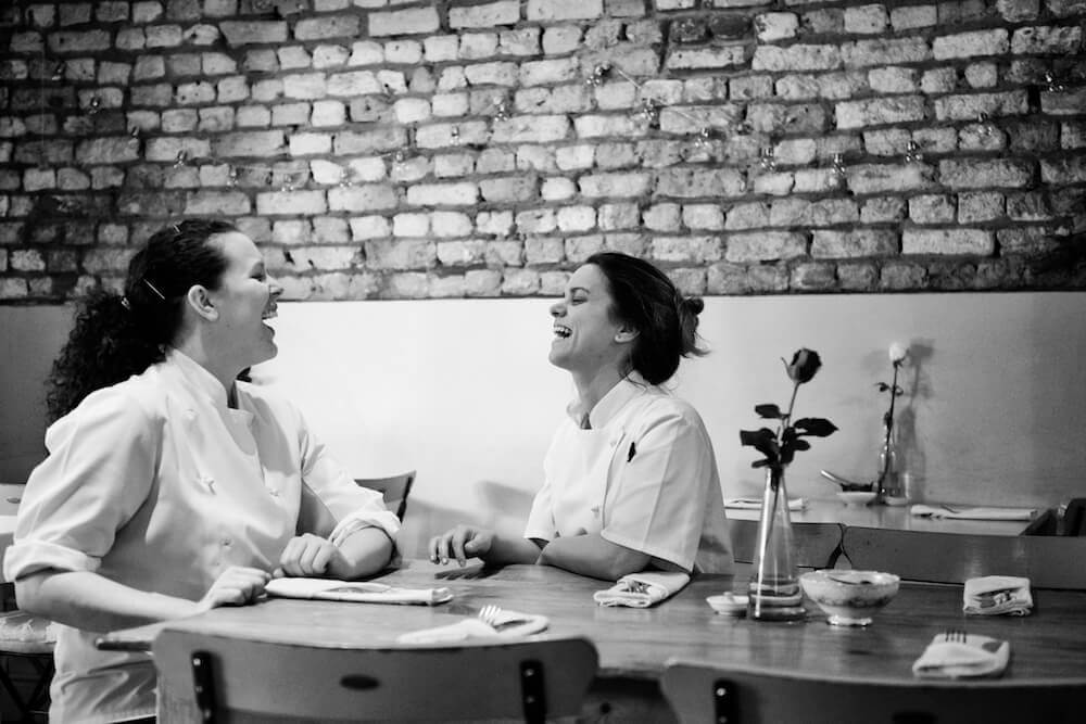 Two women laughing as they deal with negative comments online.