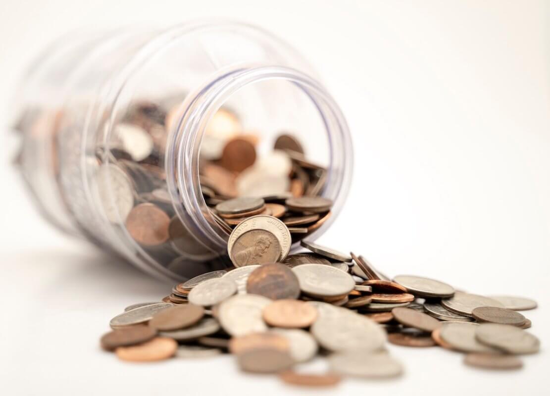 Coins spilling out of a jar in an article about finding funding for your small business.
