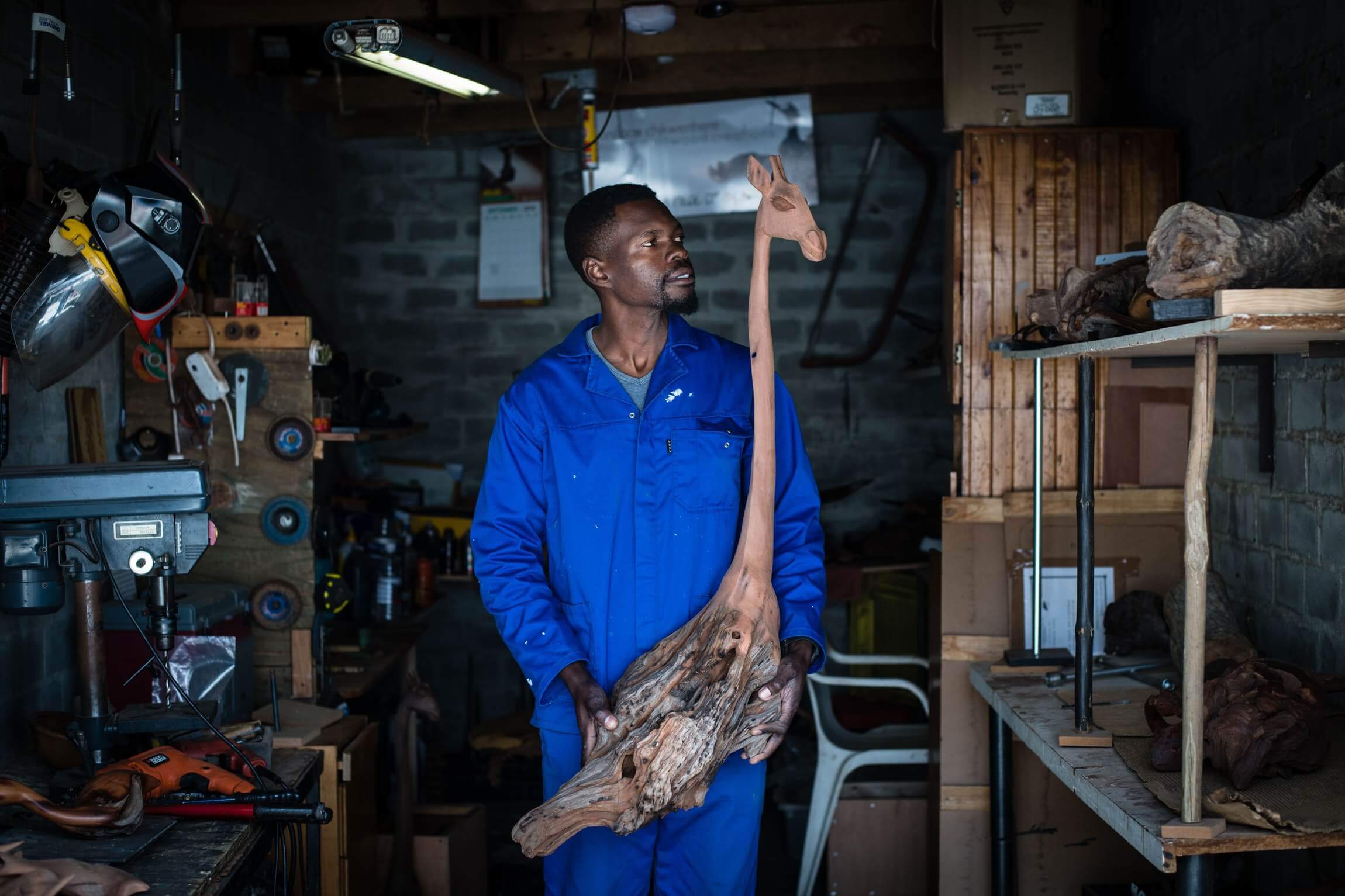 Boniface holding up a partially completed giraffe sculpture.