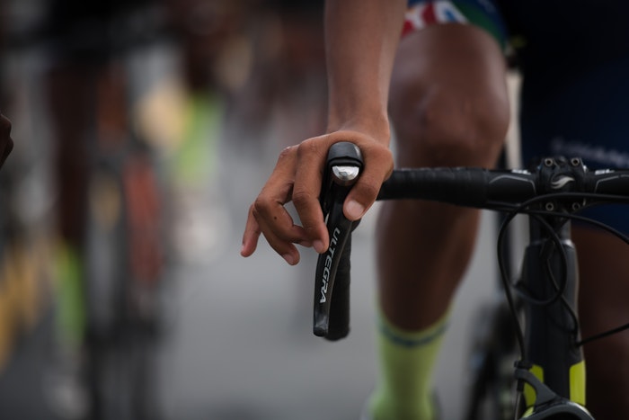 A closeup of a man holding a bicycle's handlebar.