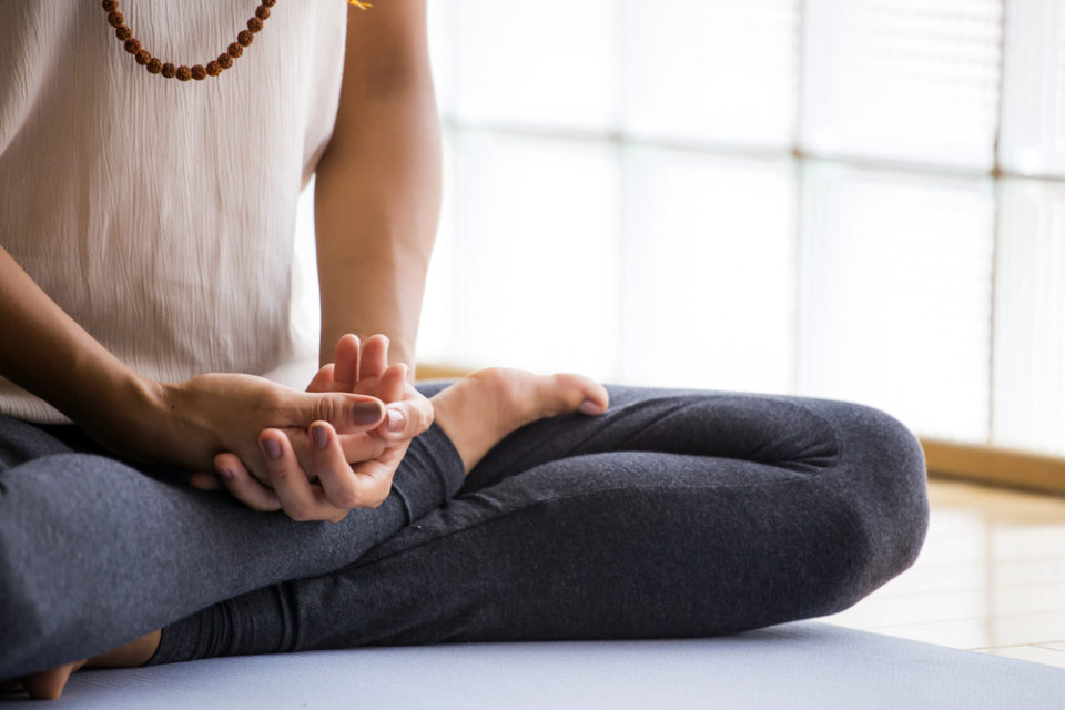 A woman sitting cross legged in article about managing the effects of your business on your health.