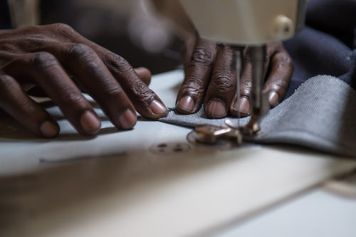 Achmed the tailor moving fabric into the sewing machine.