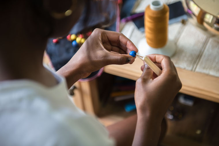 Working closely adding beads to denim jeans.