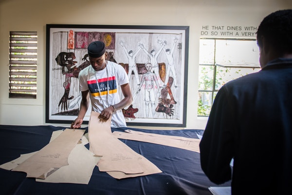 Tshepo Mohlala measuring and cutting denim to make jeans.