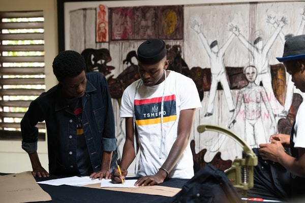 Tshepo working with the junior tailor to make a pair of jeans.